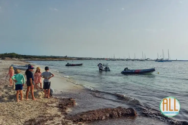 Niños junto a una barca en la playa de Cavall d'en Borras