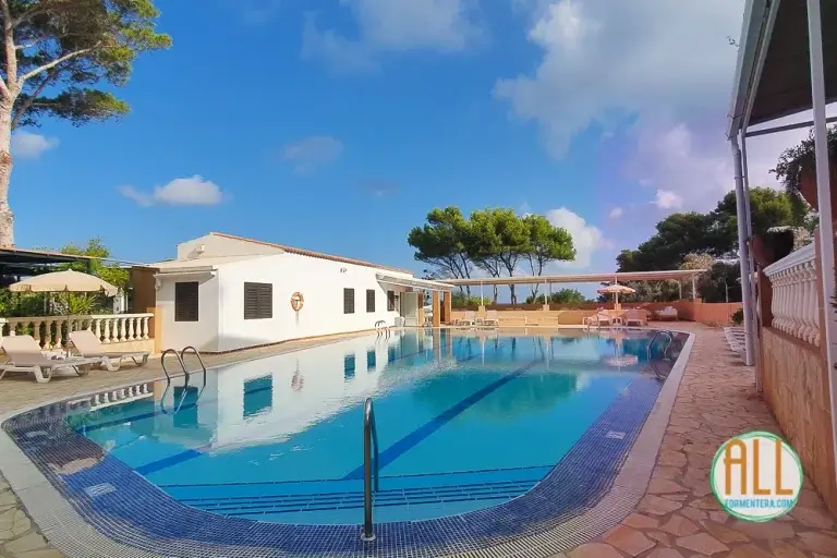 Piscina exterior del hotel Entrepinos Formentera. En primer término se encuentra la escalera de acceso a la piscina. Al fondo hay una zona de descanso